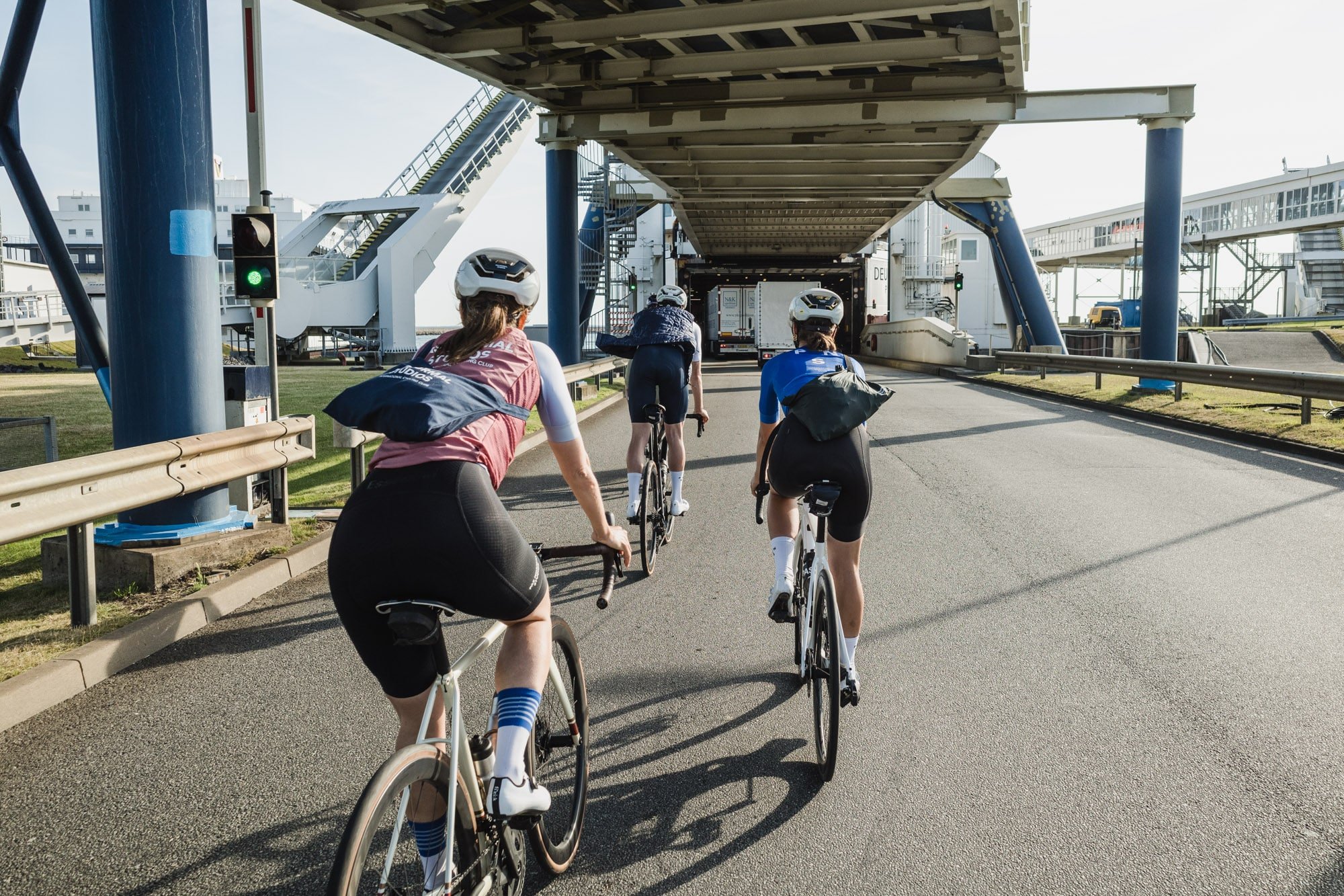 Three cyclists riding under a bridge