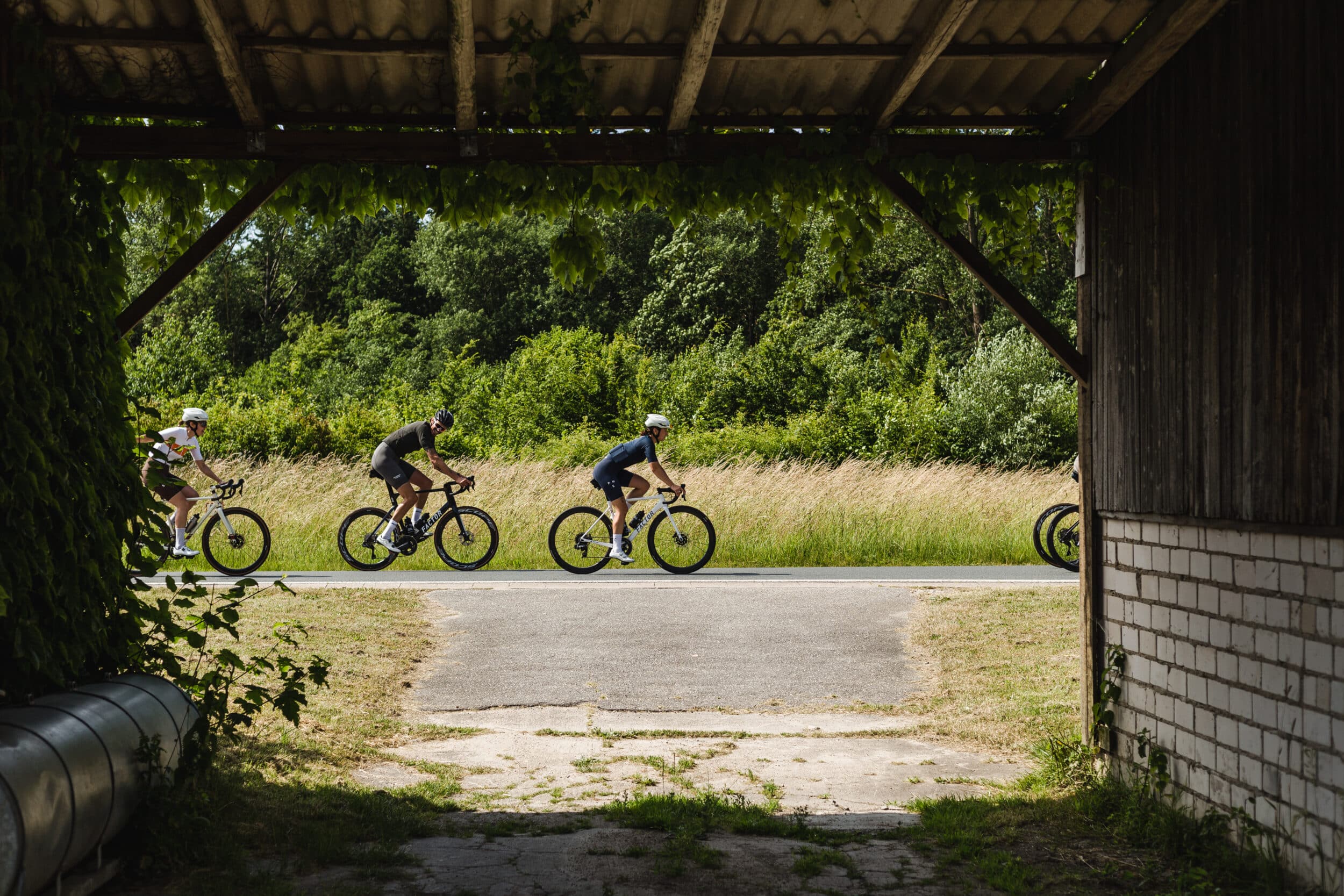 A view of three cyclists driving by riding behind each other
